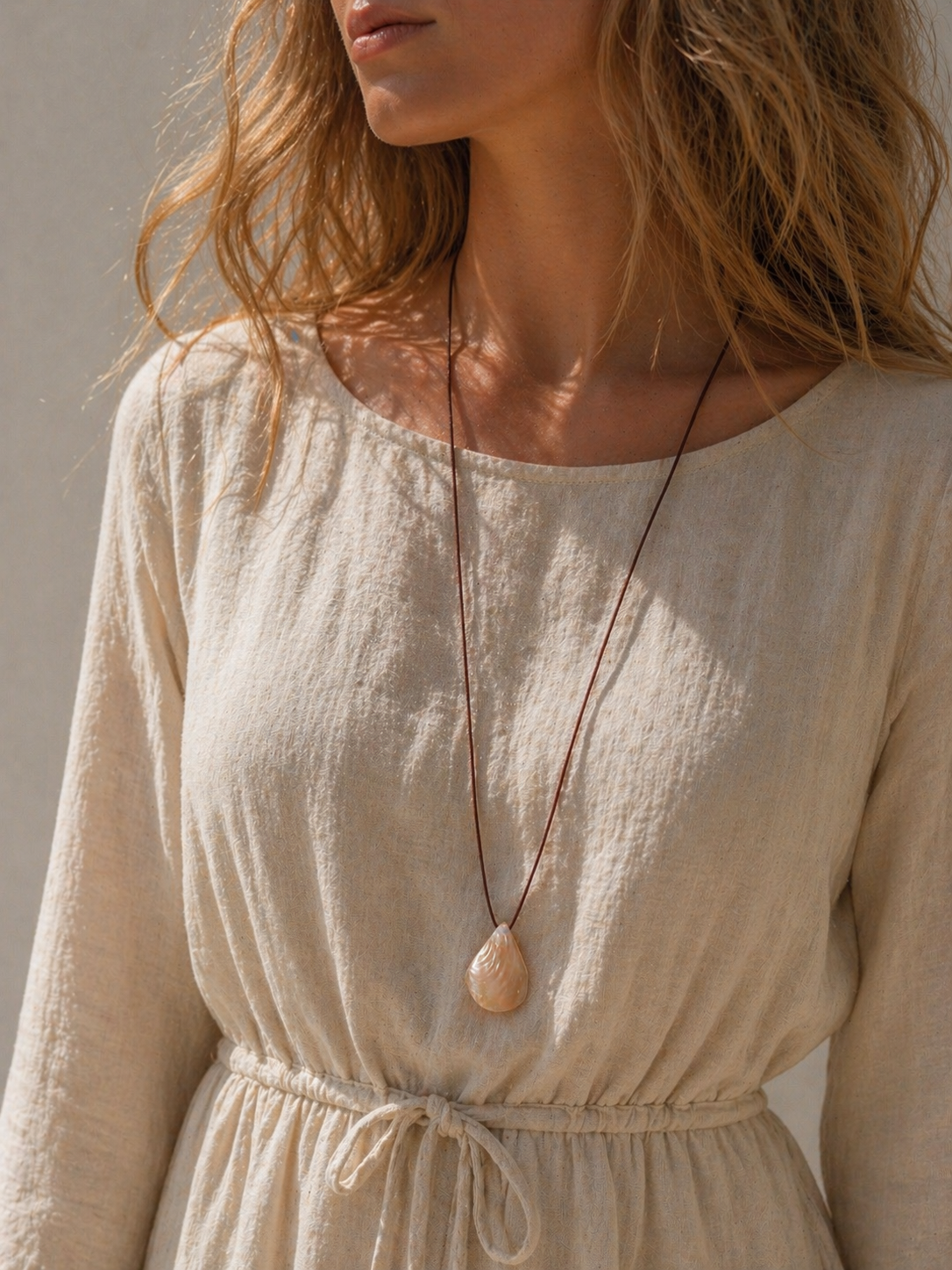 Model wearing the Summer Story Necklace, a boho beach necklace for her, featuring a mother of pearl shell charm.